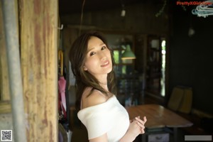 A woman in a white top and red skirt posing for a picture.