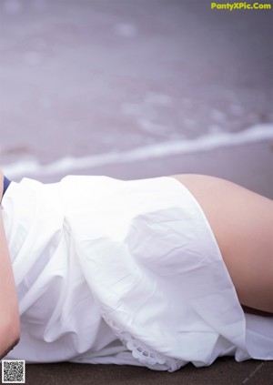 A woman in a white dress sitting on the ground.