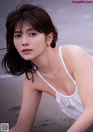 A woman in a white dress laying on the beach.