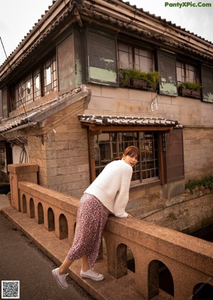 A woman in a white dress sitting on the ground.