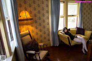 A woman in a black lingerie standing on a bed.