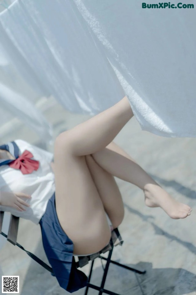 A woman sitting on a chair under a white curtain.