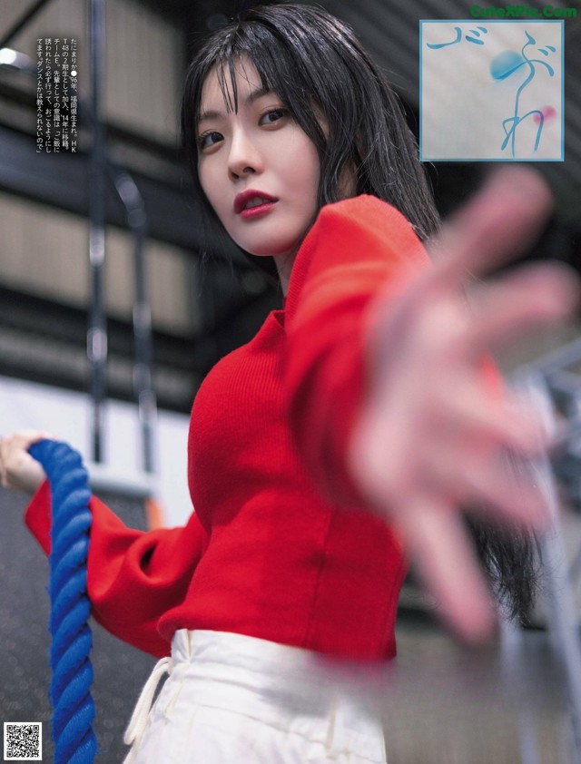 A woman in a red sweater holding a blue rope.