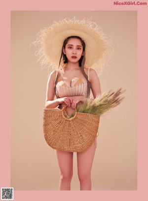 A woman sitting in a wicker chair in a pink lingerie.