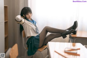 A woman in a school uniform sitting on a desk.