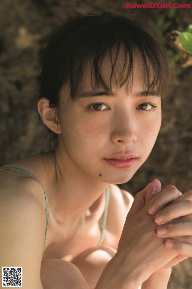 A woman in a green bikini sitting on the ground.