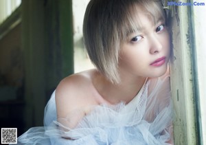 A woman in a white dress standing in front of a mirror.