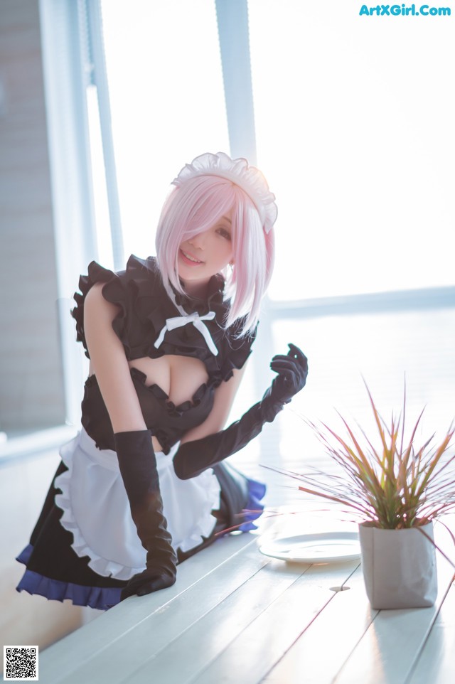 A woman in a maid outfit sitting on a table next to a plant.