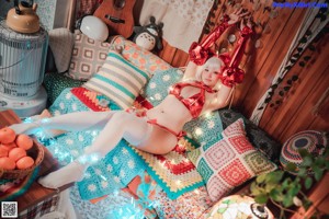 A woman in a red and white outfit sitting on a bed.