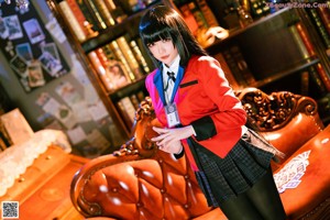 A woman in a red jacket and black skirt sitting on a couch.