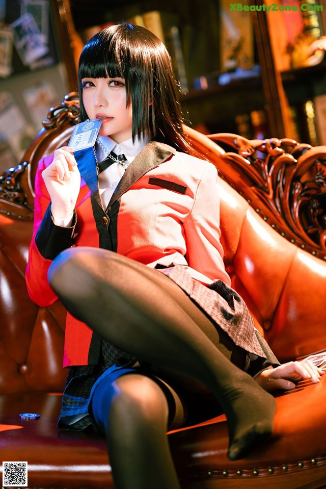 A woman sitting on a couch holding a credit card.