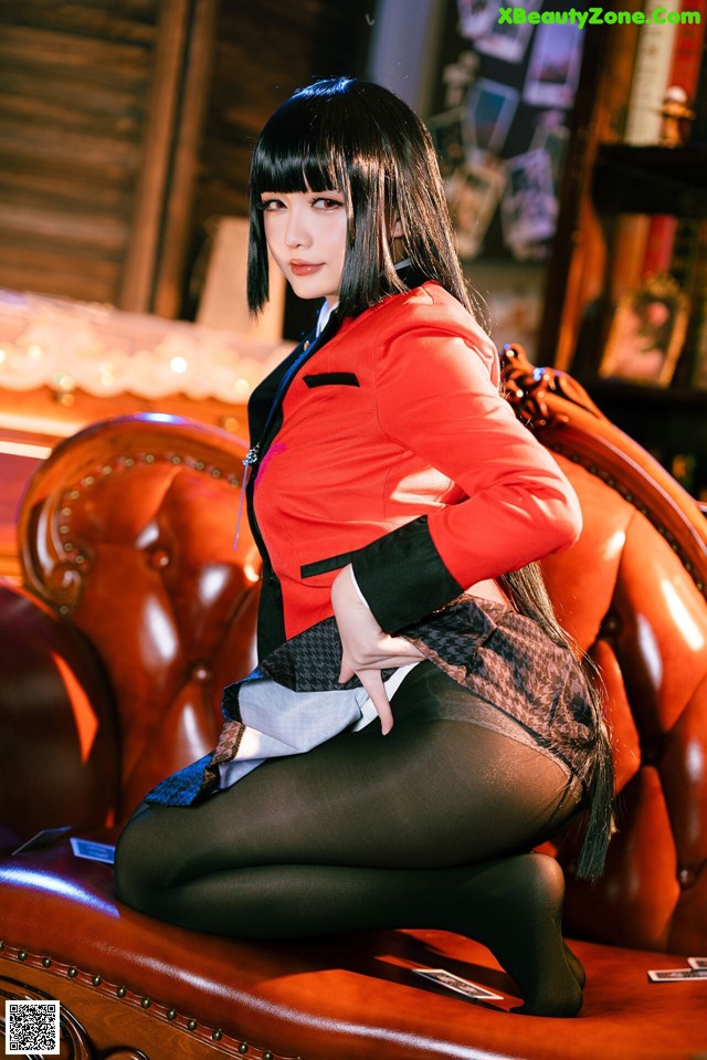 A woman in a red jacket and black pantyhose sitting on a red chair.