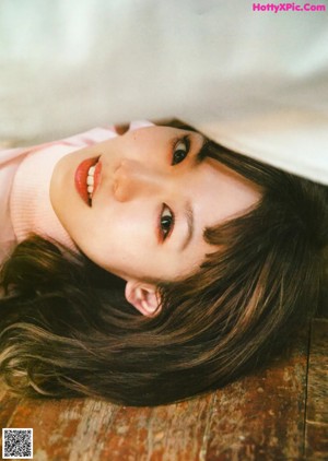 A woman laying on a bed in a beige dress.