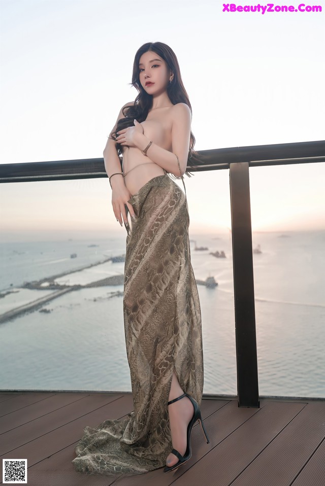 A woman standing on a balcony next to the ocean.