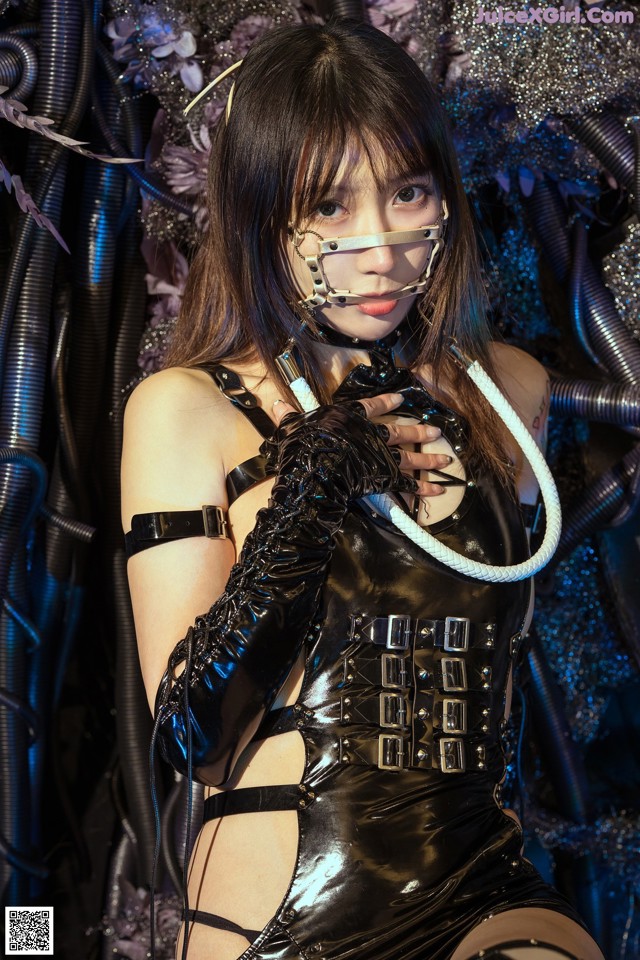 A woman in a black latex outfit holding a rope.