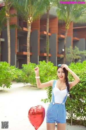 A woman in a blue and white checkered romper on a beach.