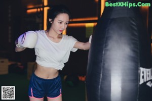 A woman standing next to a rack of dumbbells in a gym.