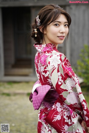 A woman in a red and white kimono is posing for a picture.