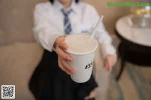 A woman in a school uniform is holding a cell phone.