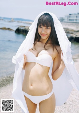 A woman in a white bikini standing on a beach.