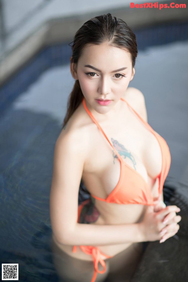 A woman in an orange bikini sitting in a pool.