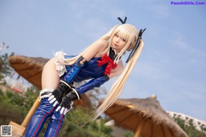 A woman in a blue and red outfit standing on a rock.