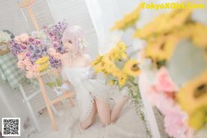 A woman sitting on a chair next to a vase of flowers.