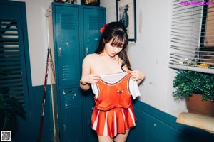 A woman in a cheerleading uniform posing in front of lockers.