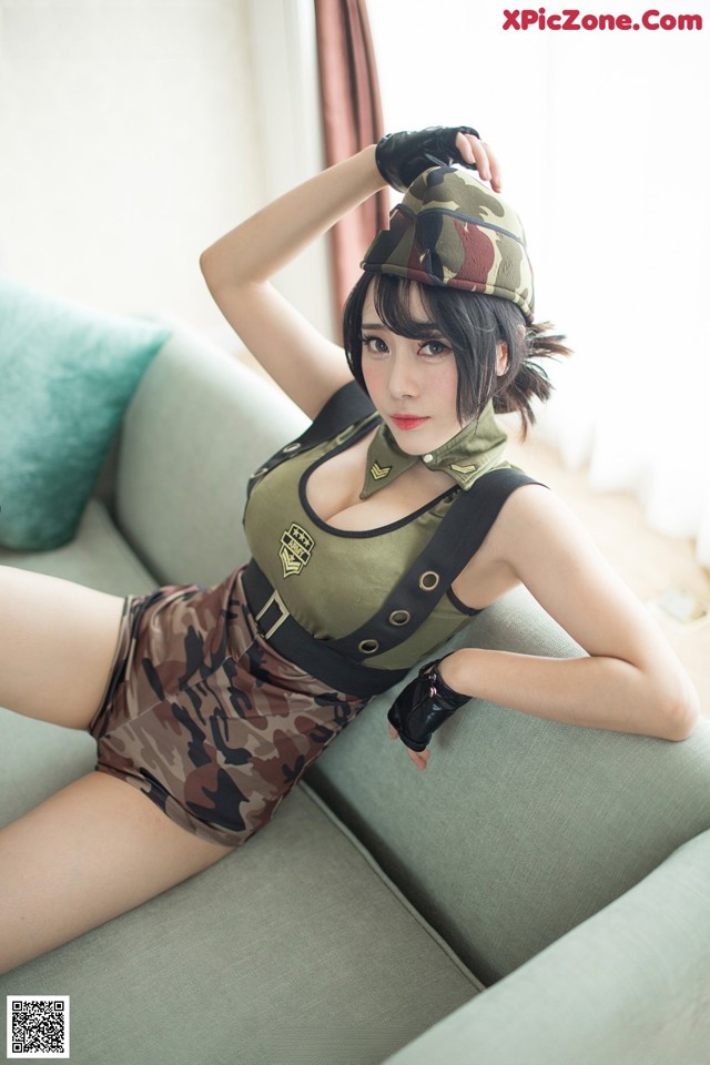 A woman in a military uniform is posing on a couch.