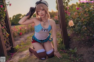 A woman in a blue top and red shorts standing in a field of flowers.