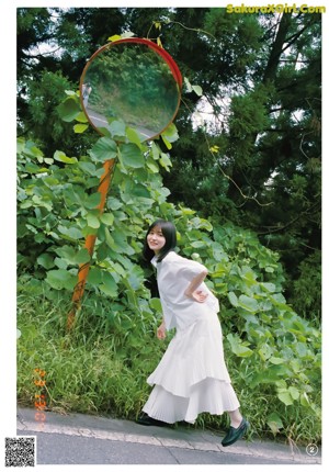 A woman leaning against a tree in a forest.