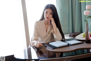 A woman sitting on top of a chair next to a window.