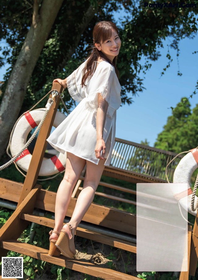 A woman in a white dress standing on a wooden bridge.