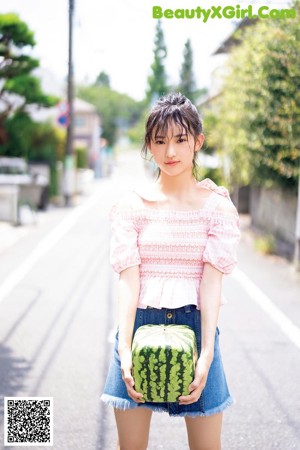 A young woman holding a watermelon in her hands.