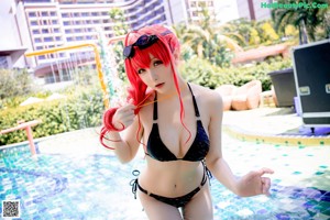 A woman in a black bikini standing next to a pool.