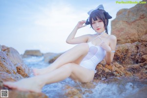 A woman in a white bikini standing on a beach.