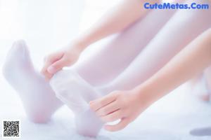 A woman in white stockings and stockings sitting on a bed.