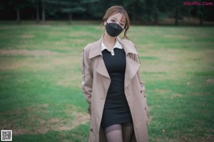 A woman wearing a face mask standing on top of a traffic cone.