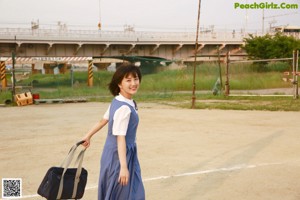 A young woman in a blue and white dress holding a green leaf.