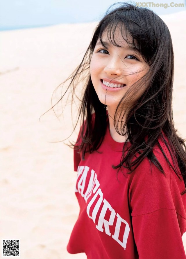 A woman in a red sweatshirt standing on a beach.