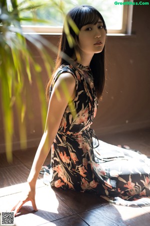 A woman with long black hair standing in front of a window.