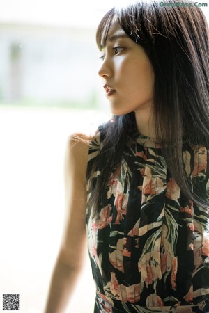 A woman in a floral dress sitting on the floor.