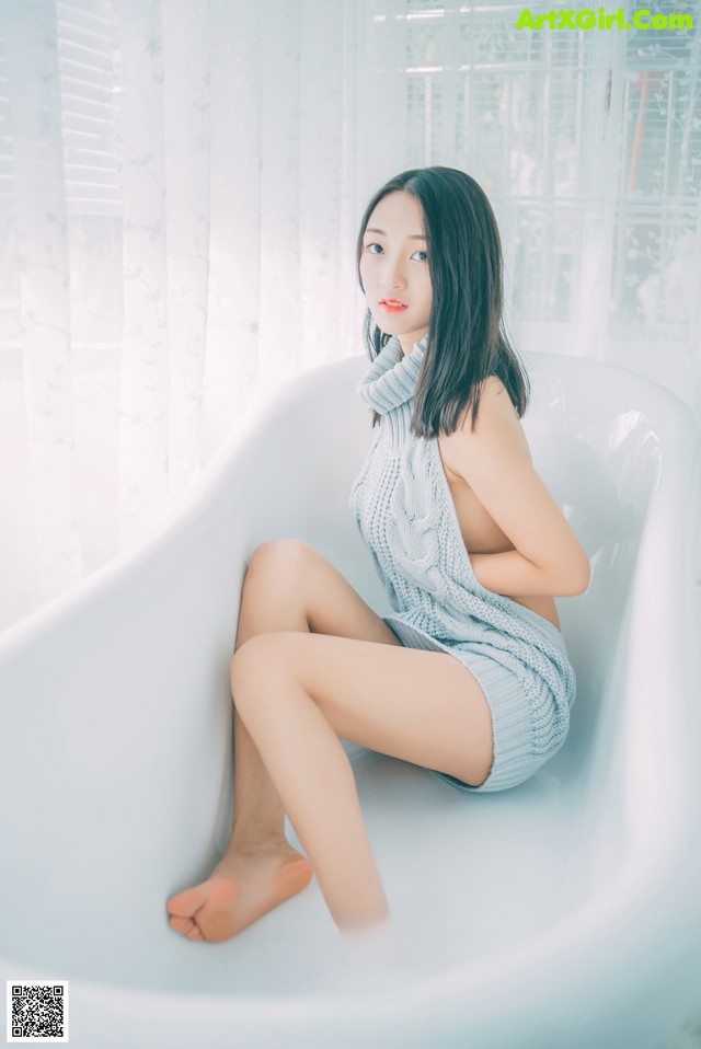 A woman sitting in a bathtub with her legs crossed.