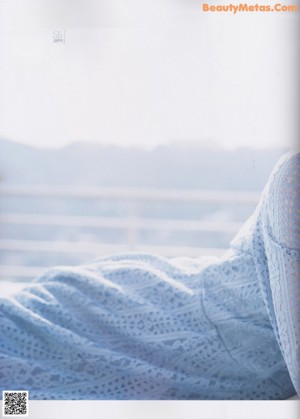 A woman in a blue and white striped shirt is posing for a magazine.