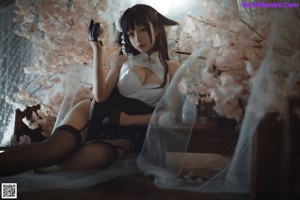 A woman in lingerie sitting on a bed next to a window.
