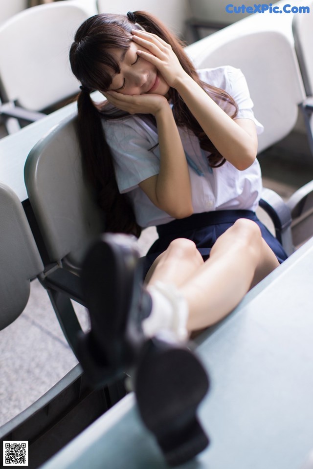 A woman sitting on a bench with her head in her hands.