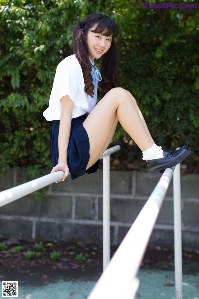 A woman in a school uniform is sitting on a railing.