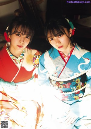 Two women in kimonos standing next to each other. 