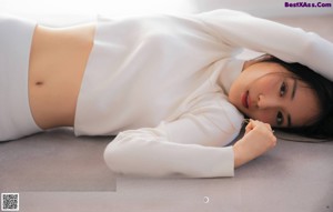 A woman laying on a bed in a blue and white checkered shirt.