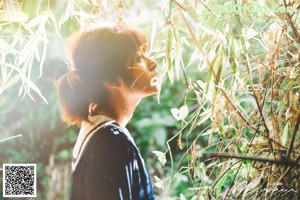 A woman standing in the middle of a lush green forest.